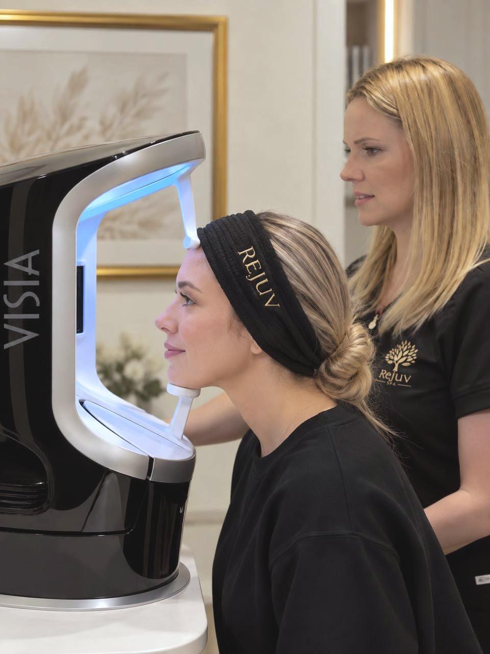A guest resting her chin on the skin-analysis camera while a provider positions it